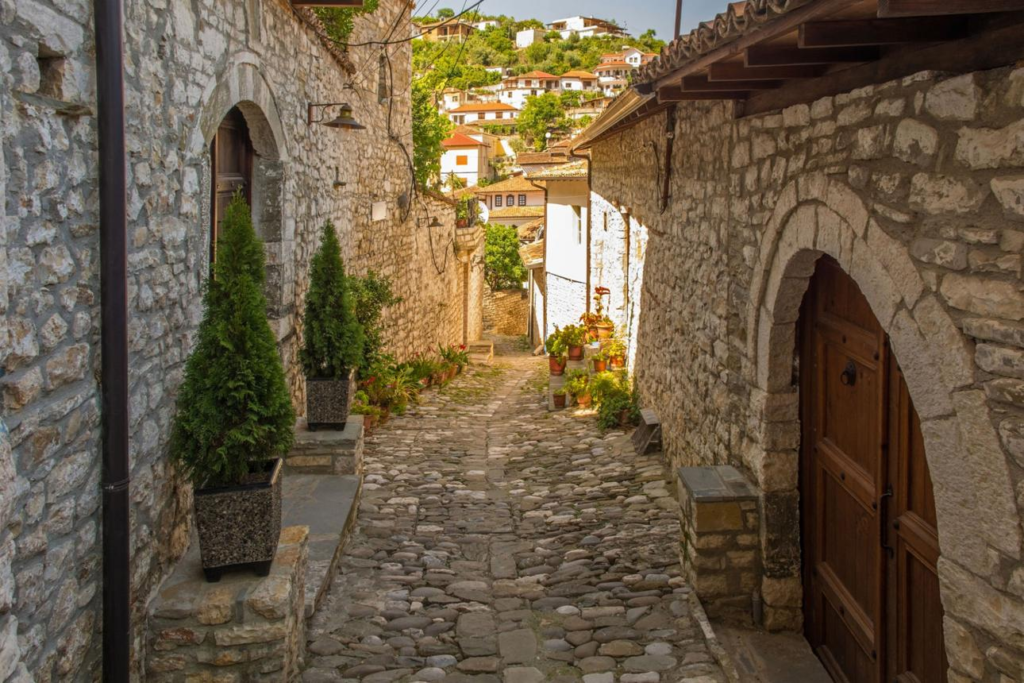 Visitors walking through Berat's cobblestone streets lined with traditional white Ottoman houses.