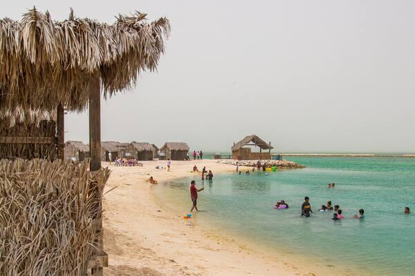 Visitors relaxing on a sandy beach with turquoise waters surrounding the Al Dar Islands.