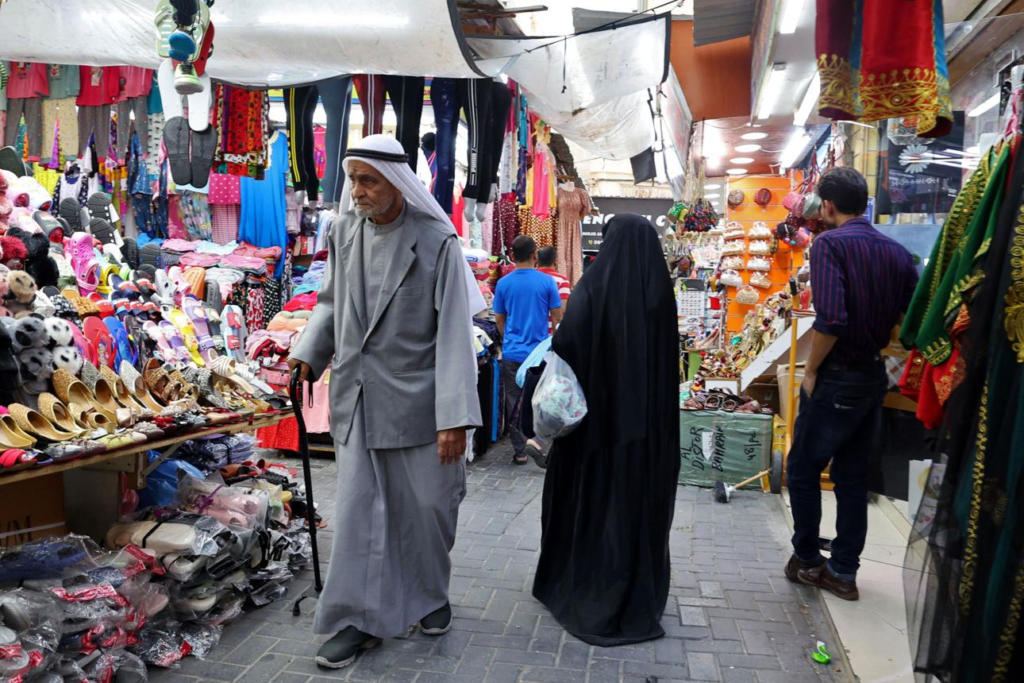 Visitors exploring the bustling lanes of Manama Souq filled with traditional shops and local products.
