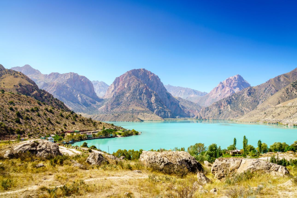 Crystal-clear waters of Iskanderkul Lake surrounded by mountains in Tajikistan.